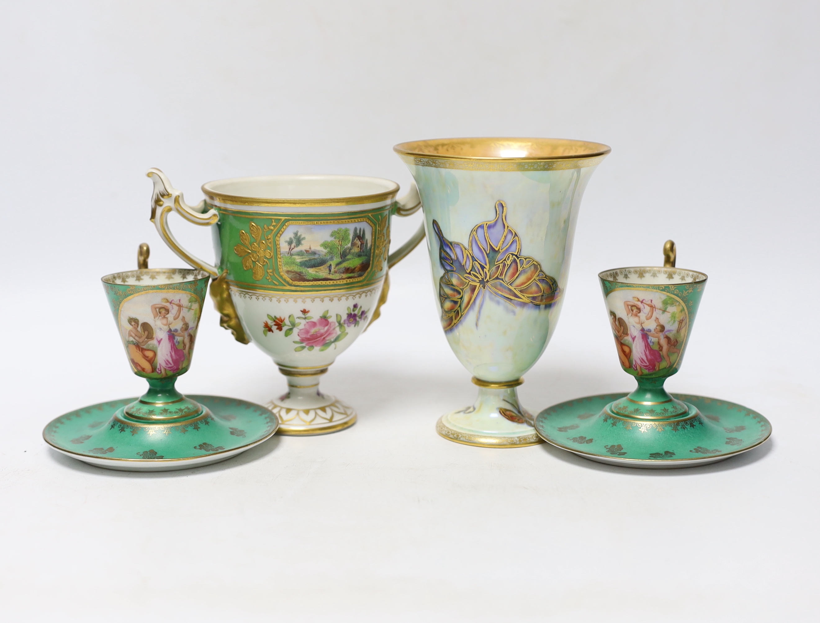 A Continental porcelain twin handled trophy cup with landscape vignettes, together with a pair of Continental liqueur cups and dishes, and a Wedgwood butterfly lustre posy vase, design number Z4832, vase 13.5cm high (4)
